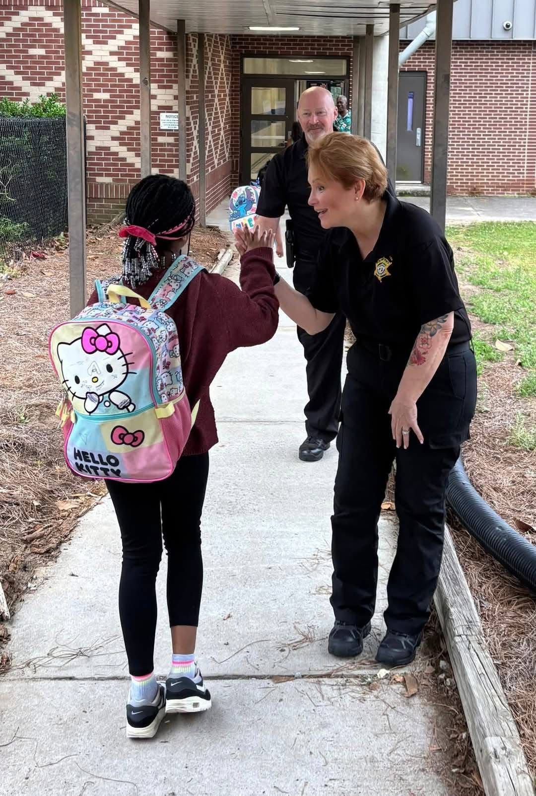 Lisa Davey giving a high five to a student walking into school