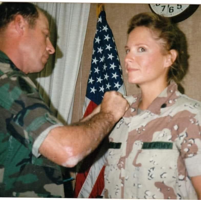 Lisa Davey in desert uniform at a ceremony in front of the American flag